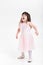 Beautiful little girl in pink Princess dress naughty on a gray b