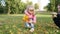 Beautiful little girl playing in the autumn city park collects fallen leaves and makes a bouquet