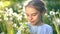 Beautiful little girl playing with flowers at summer day.