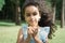 Beautiful little girl portrait in summer park eating fast food hamburger or cheeseburger