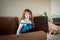 Beautiful little girl sitting on couch in living room and using laptop computer.Online training, games and watching cartoons. New