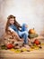 Beautiful little girl sitting among pumpkins wearing autumn wreath