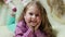 Beautiful little girl smiling at camera. Portrait of cheerful kid lying on couch