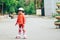 Beautiful little girl stands on roller skates in a city park. The child in a helmet and protective equipment rides on rollers