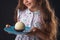 Beautiful little girl surprised from a tasty big chocolate coconut candy as a ball. Kid ready to eat cake