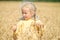 Beautiful little girl walking in field of wheat