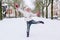 Beautiful little girl wearing in jeans, white down jacket and knitted hat jumping in snow outdoors