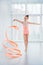 Beautiful little gymnast girl in pink sportswear dress, doing rhythmic gymnastics exercise Spirals with art ribbon