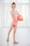 Beautiful little gymnast girl in pink sportswear dress, performing art gymnastics element with ball in fitness class