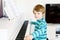 Beautiful little kid boy playing piano in living room or music school