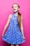 Beautiful little redhead girl in blue dress posing like model on pink background.