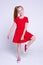 Beautiful little redhead girl in red dress and sneakers posing like model on white background.