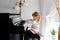 Beautiful little toddler girl playing piano in living room. Cute preschool child having fun with learning to play music