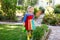 Beautiful little toddler girl in yellow rubber boots and colorful dress watering spring flowers with kids water can