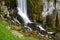 Beautiful long exposure photo of a waterfall rushing down a cliff and bursting onto a steep rocky mountainside