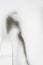 Beautiful and long hair woman body silhouette behind a diffuse curtain