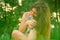 Beautiful long-haired brunette girl in a park sitting with a cat. The girl growls at the cat and bites. Photoshoot with a pet cat