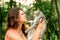 Beautiful long-haired brunette girl in a park sitting with a cat. The girl growls at the cat and bites. Photoshoot with a pet cat