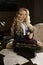 Beautiful long haired curly blonde schoolgirl tiredly learns homework in a classic vintage interior room, sitting at a table