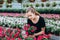 Beautiful long-haired girl in a greenhouse with flowers petunias in spring