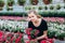 Beautiful long-haired girl in a greenhouse with flowers petunias in spring