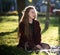 Beautiful long-haired girl sits on a plaid in the autumn park and looks away