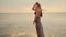 Beautiful long-haired girl walks on the beach at sunset. Anamorphic shot