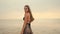 Beautiful long-haired girl walks on the beach at sunset. Anamorphic shot