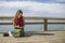 Beautiful long haired woman writing in journal near rural lake.