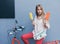 Beautiful long-haired young blonde woman makes a choice of ice cream sitting on a red vintage bike