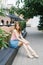 Beautiful long-legged cute model girl sitting on the terrace of a summer cafe.