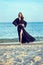 Beautiful long legged woman wearing trendy chiffon oriental black chiffon beach cover up stepping lightly on the sand