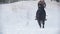 Beautiful longhaired female rider wild and fast riding black horse through the snow, dog running nearby, slow-motion