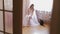 Beautiful and lovely bride in wedding dress sit on a chair and look at her shoes. Cat sits near woman. Wedding morning