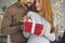 Beautiful loving young couple woman and man hugging and holding red holiday present box with gift