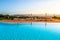 Beautiful luxury swimming pool with bright blue water, umbrellas and sunbeds in Tuscan landscape. Evening summer sunset