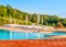 Beautiful luxury swimming pool with bright blue water, umbrellas and sunbeds in Tuscan landscape. Evening summer sunset