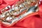 Beautiful macro photo of the details of a wind instrument of a golden alto saxophone on a red background