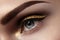 Beautiful macro shot of female eye with ceremonial makeup. Perfect shape of eyebrows, eyeliner and pretty gold line on eyelid