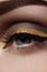 Beautiful macro shot of female eye with ceremonial makeup. Perfect shape of eyebrows, eyeliner and pretty gold line on eyelid