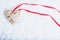 Beautiful magical vintage beige heart tied with a red ribbon on a white snow background. Winter and Christmas concept