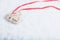 Beautiful magical vintage beige heart tied with a red ribbon on a white snow background. Winter and Christmas concept