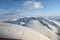 Beautiful and majestic snowy mountain landscape with ocean in the background with aircraft wings