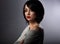 Beautiful makeup woman with short black hairstyle looking serious on grey background. Closeup portrait