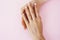 Beautiful manicured woman hands on pink background, wearing wedding ring