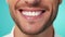 Beautiful mans smile with healthy white, straight teeth close-up on one tone background with space for text