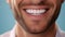 Beautiful mans smile with healthy white, straight teeth close-up on one tone background with space for text