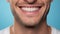 Beautiful mans smile with healthy white, straight teeth close-up on one tone background with space for text