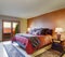 Beautiful master bedroom with red bedding and beige walls.