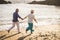 Beautiful mature couple outdoor in leisure activity run together at the beach on the shore hanging the hands and living together
